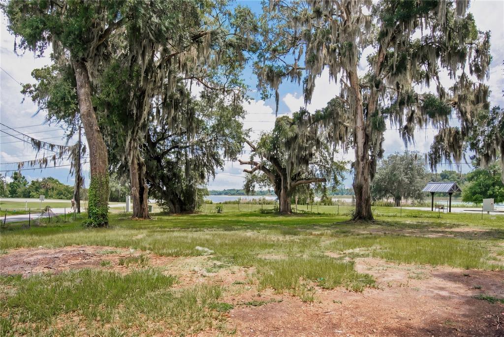 A grassy lot features several large, moss-draped oak trees with a view of a distant lake — 720 HUNTINGTON ROAD, CRESCENT CITY, FL
