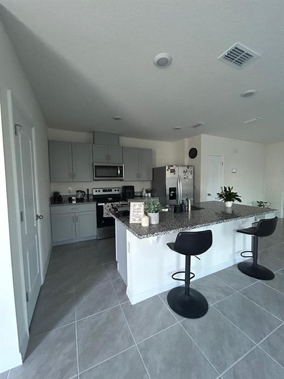 A kitchen features gray cabinets, granite countertops, a large island, and tile flooring — 2000 RANKIN STREET, KISSIMMEE, FL