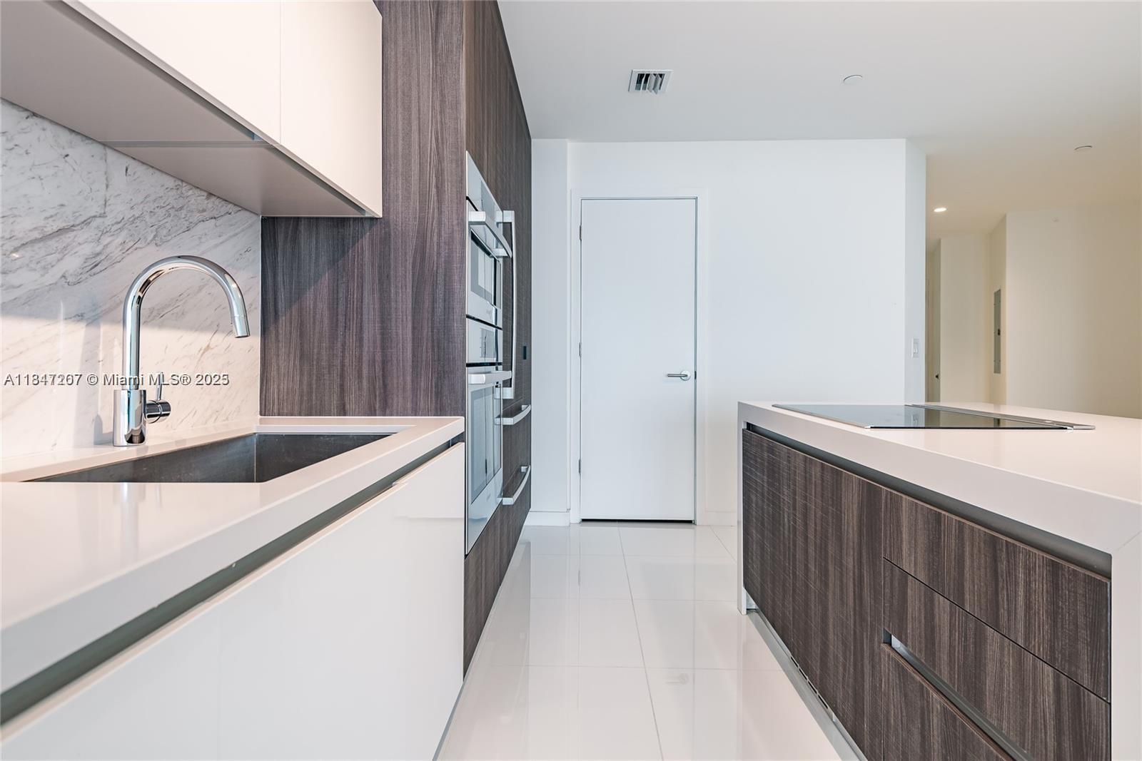 A modern kitchen features white countertops, dark wood cabinetry, and a stainless steel sink — 851 NE 1st Ave # 2100, Miami FL 33132, MIAMI, FL
