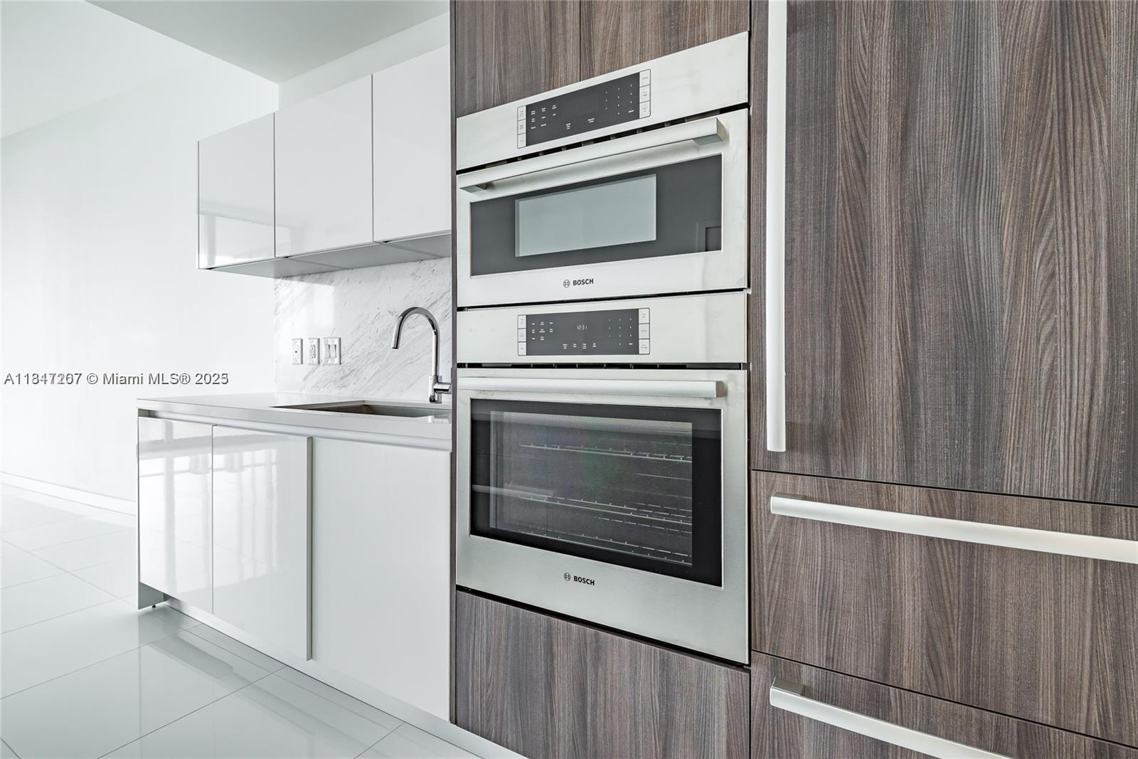 A modern kitchen features white cabinets, marble backsplash, and a stacked Bosch oven unit — 851 NE 1st Ave # 2100, Miami FL 33132, MIAMI, FL