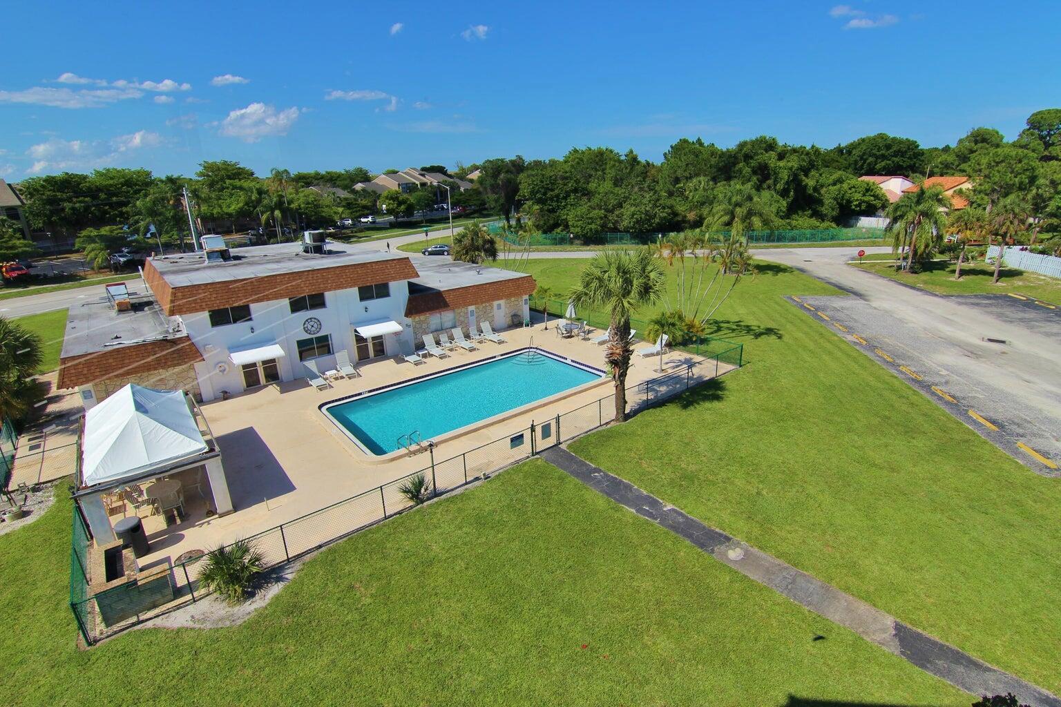 An aerial view shows a swimming pool and patio area next to a two-story building — 6289 Lear Drive # 301, Lake Worth FL 33462, LAKE WORTH, FL