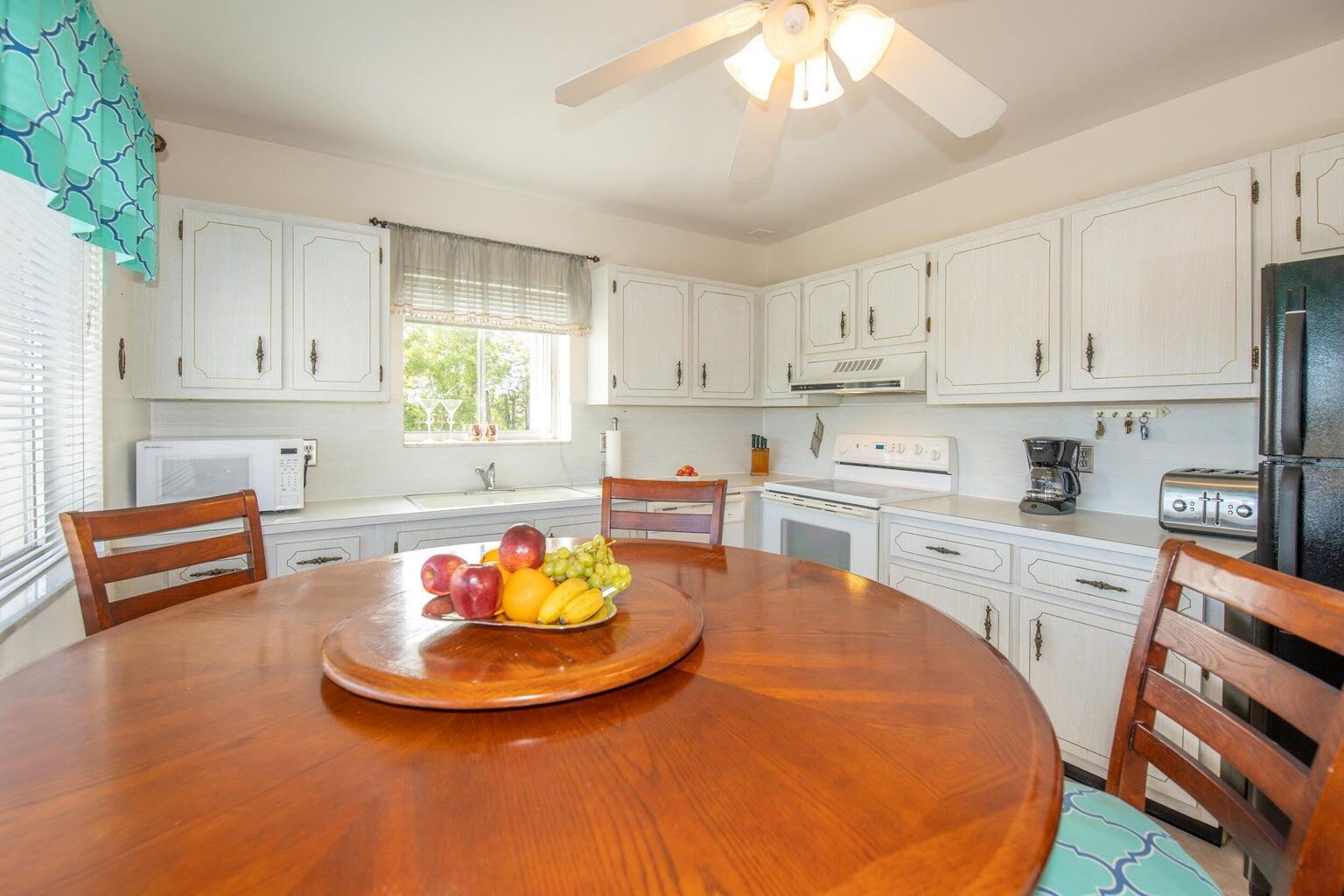 A kitchen with white cabinets, a round wooden dining table, and a ceiling fan — 6289 Lear Drive # 301, Lake Worth FL 33462, LAKE WORTH, FL