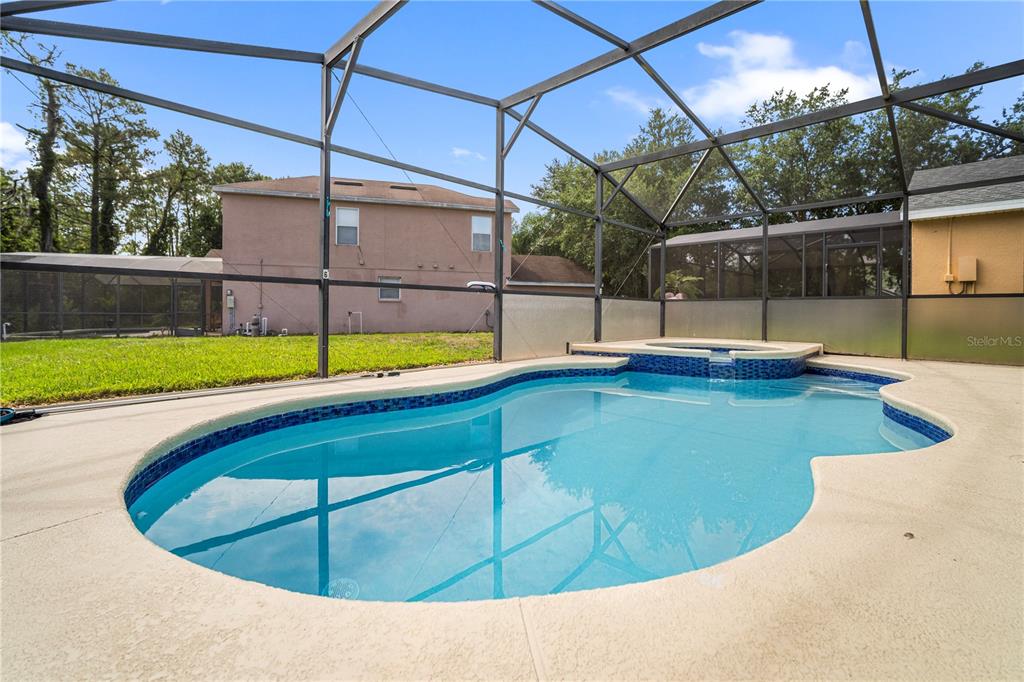 A swimming pool with an attached spa is enclosed by a screened lanai — 126 SUNDOWN COURT, DAVENPORT, FL