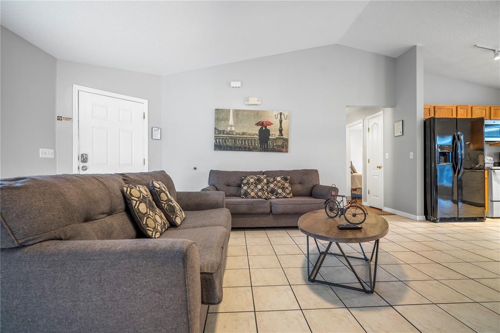 A living room features two gray sofas, a round coffee table, and light tile flooring — 126 SUNDOWN COURT, DAVENPORT, FL