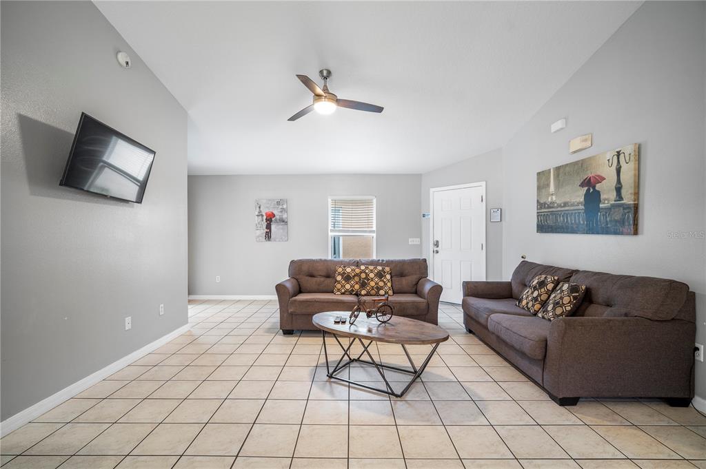 A living room features light gray walls, tile flooring, two brown sofas, and a ceiling fan — 126 SUNDOWN COURT, DAVENPORT, FL