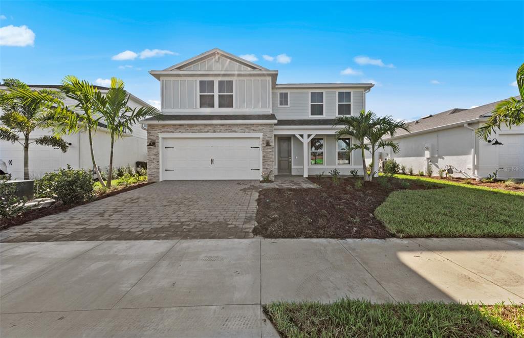 A two-story house with a stone-accented facade, a two-car garage, and a paved driveway — 7617 FULHAM AVENUE, BRADENTON, FL