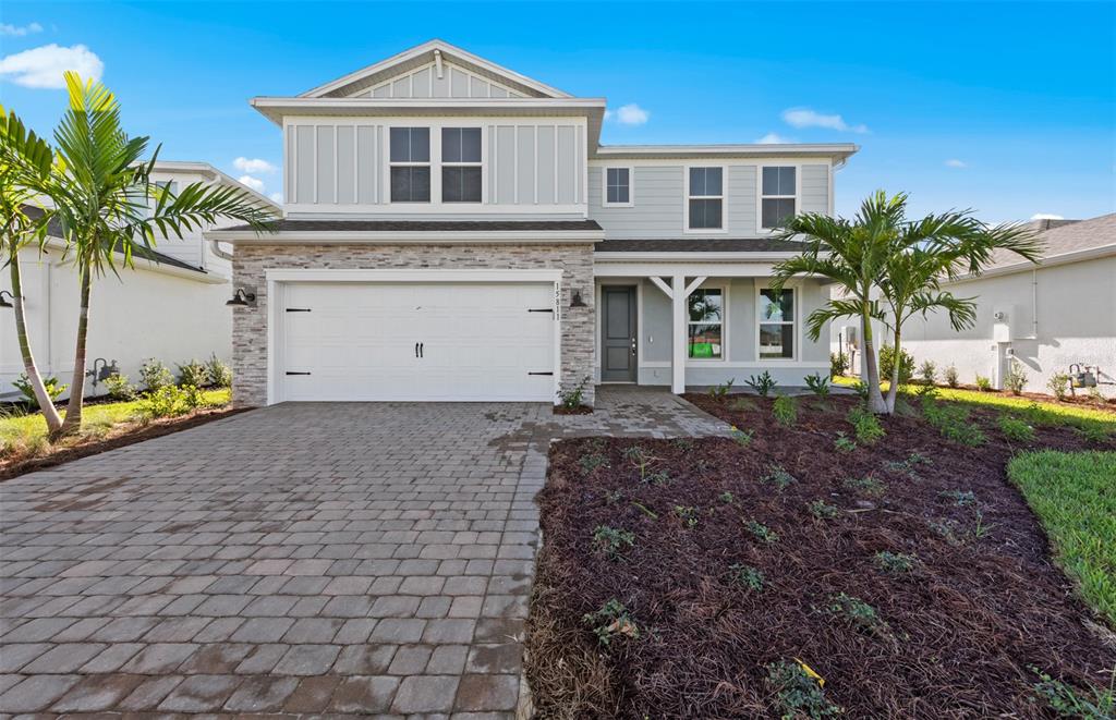 A two-story house with a stone-accented garage, light siding, and a paved driveway — 7617 FULHAM AVENUE, BRADENTON, FL