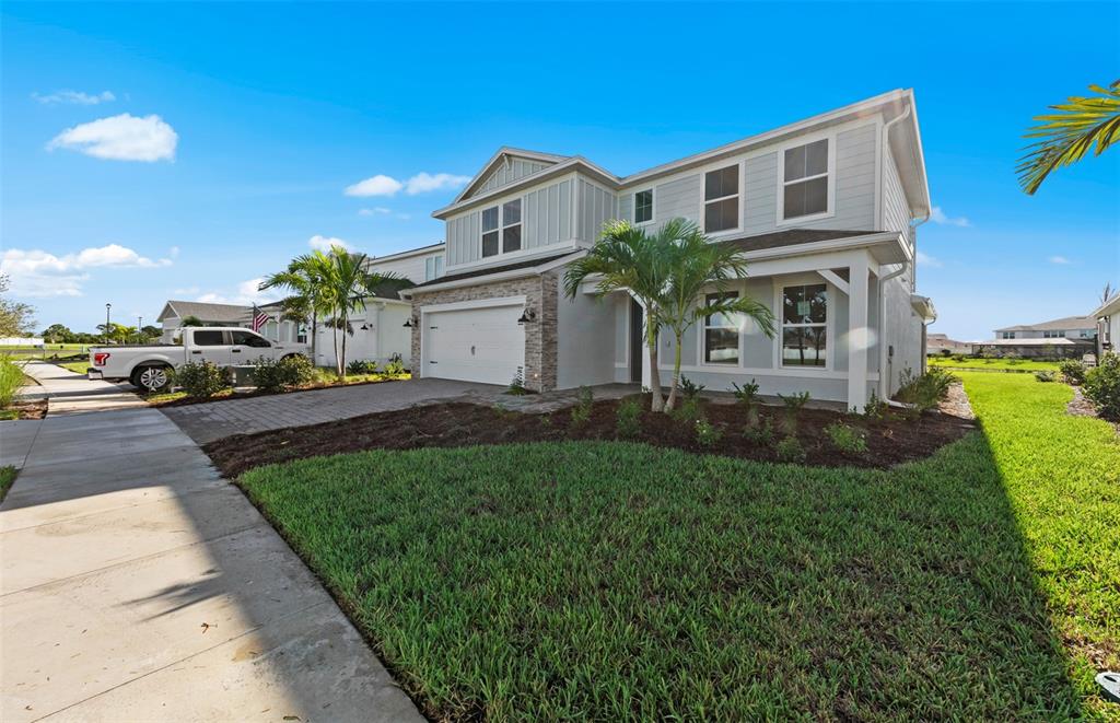 A two-story light gray house with a stone-accented garage and a front lawn — 7617 FULHAM AVENUE, BRADENTON, FL