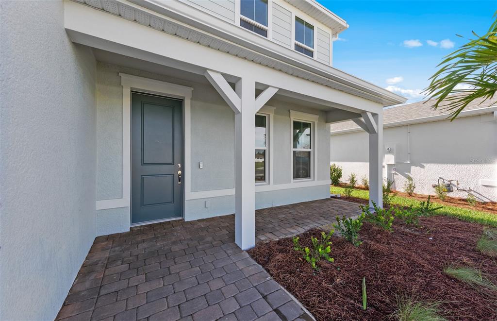 A paved walkway leads to the front door of a house with a covered porch — 7617 FULHAM AVENUE, BRADENTON, FL