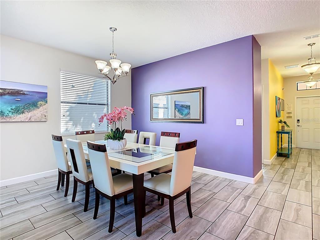 A dining room features a white table, six chairs, a purple accent wall, and tile flooring — 5528 SOLTERRA CIRCLE, DAVENPORT, FL