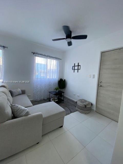 A living room featuring a light gray sectional sofa, a ceiling fan, and tile flooring — 0 Avenida la Gaviota # 403, NY 11503, NY