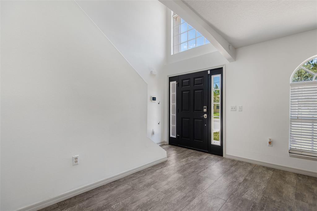 An entryway features a black front door, high ceilings, and gray wood-look flooring — 14 LLEWELLYN TRAIL, PALM COAST, FL