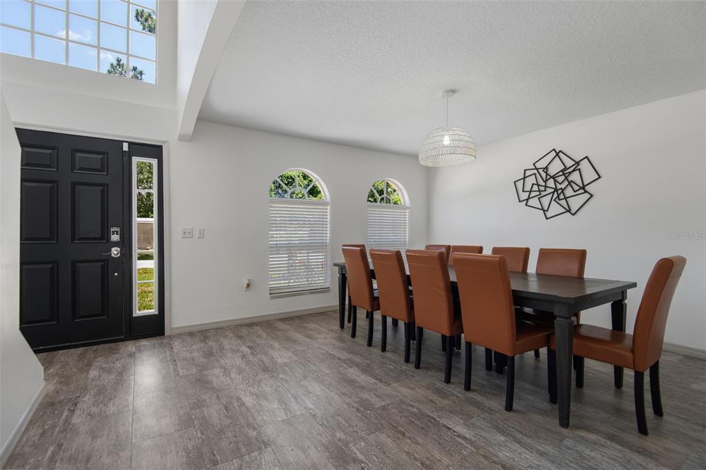 A dining room features a dark wood table, brown chairs, white walls, and gray flooring — 14 LLEWELLYN TRAIL, PALM COAST, FL