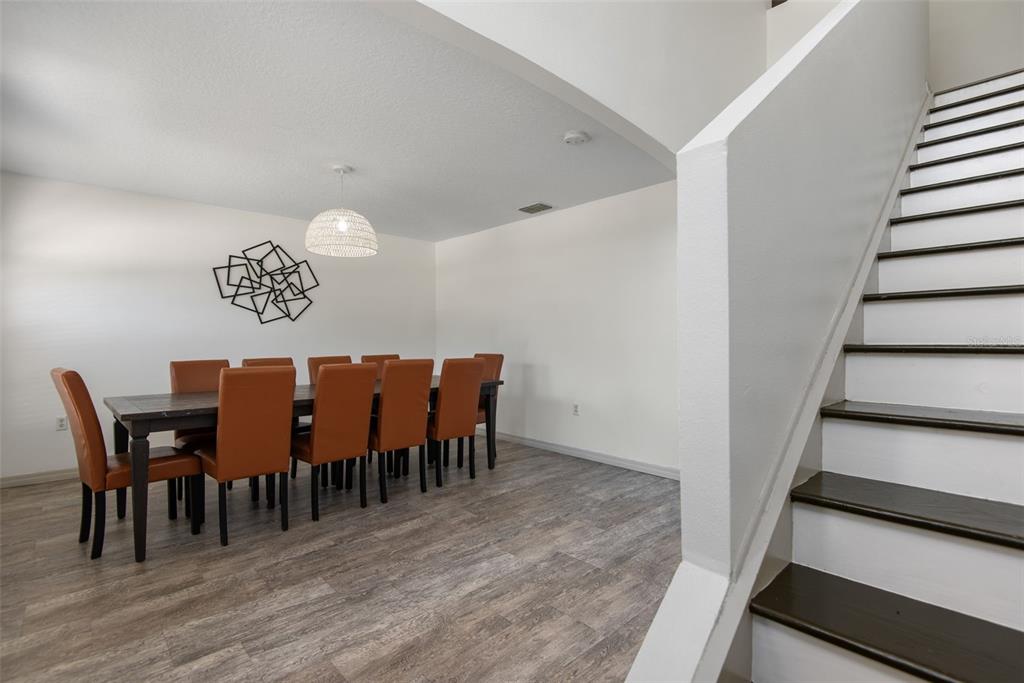 A dining area with a wooden table, brown chairs, and a staircase on the right — 14 LLEWELLYN TRAIL, PALM COAST, FL