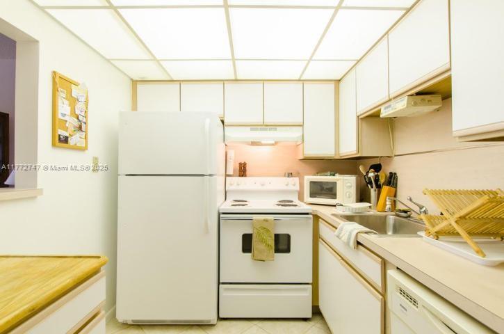 A kitchen features white appliances, light-colored cabinetry, and a grid-patterned drop ceiling — 251 Mansfield F # 251F, Boca Raton FL 33434, BOCA RATON, FL