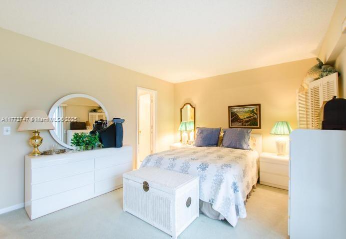 A bedroom features a white dresser, a bed with blue pillows, and a white trunk — 251 Mansfield F # 251F, Boca Raton FL 33434, BOCA RATON, FL