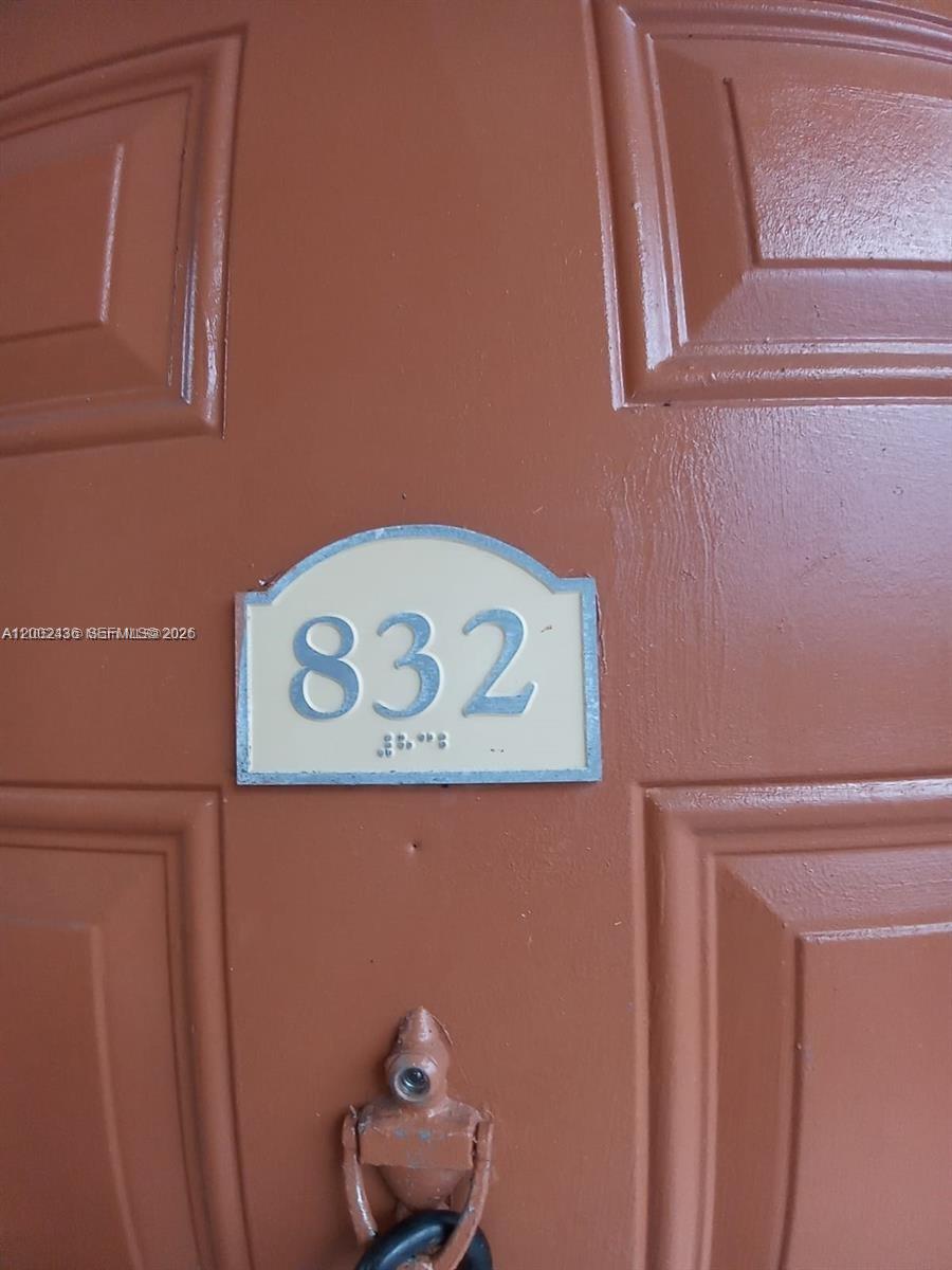 A close-up view of a brown door featuring a room number sign labeled 832 — TAMARAC, FL