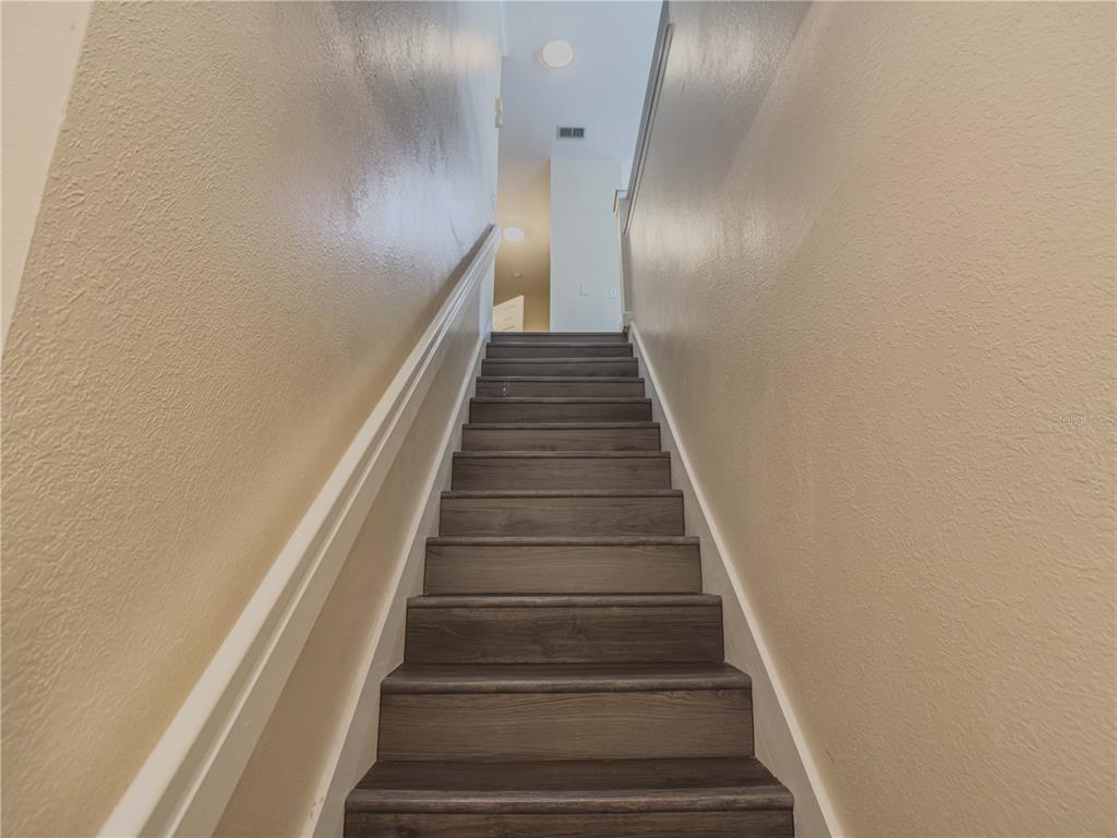 A straight staircase with dark wood-look treads leads to an upper landing — 2226 ARBOR LAKES CIRCLE, SANFORD, FL