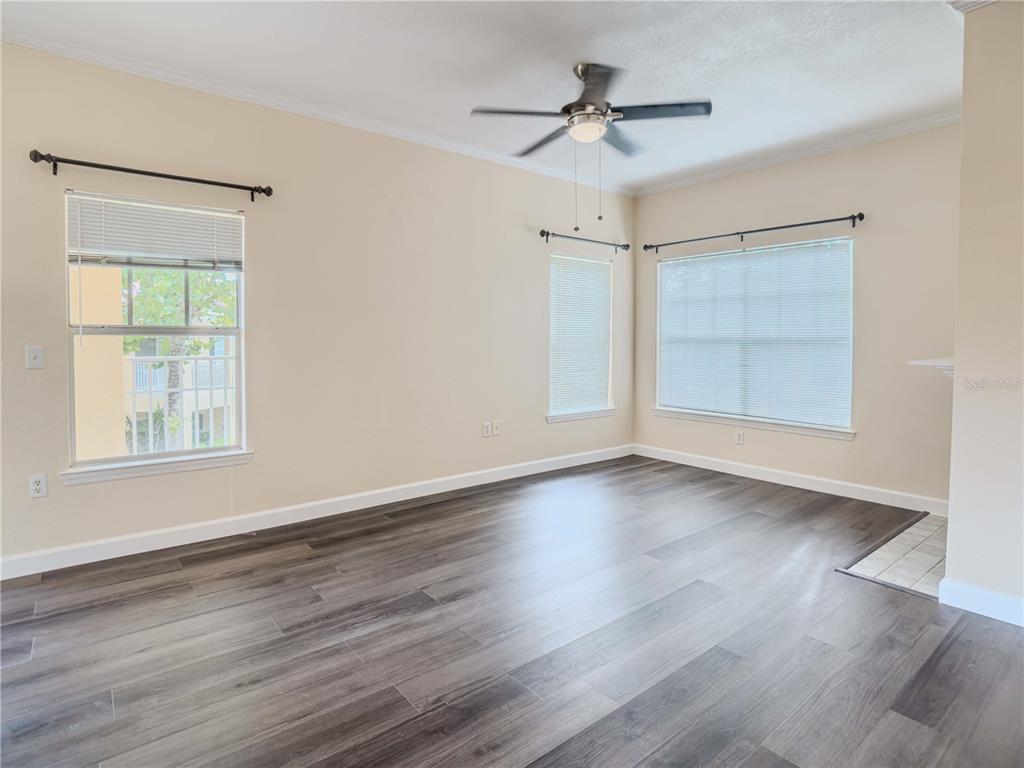 An empty room features wood-look flooring, a ceiling fan, and three windows with blinds — 2226 ARBOR LAKES CIRCLE, SANFORD, FL