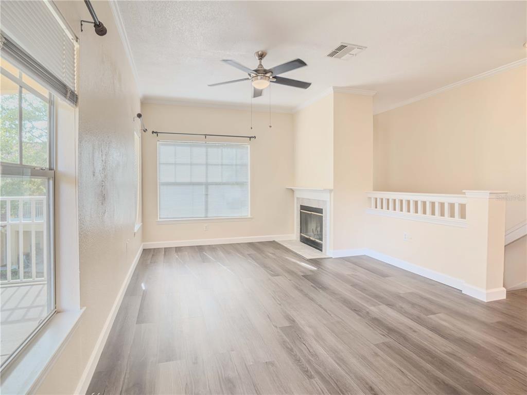 A living room features wood-look flooring, a ceiling fan, a fireplace, and a white railing — 2226 ARBOR LAKES CIRCLE, SANFORD, FL