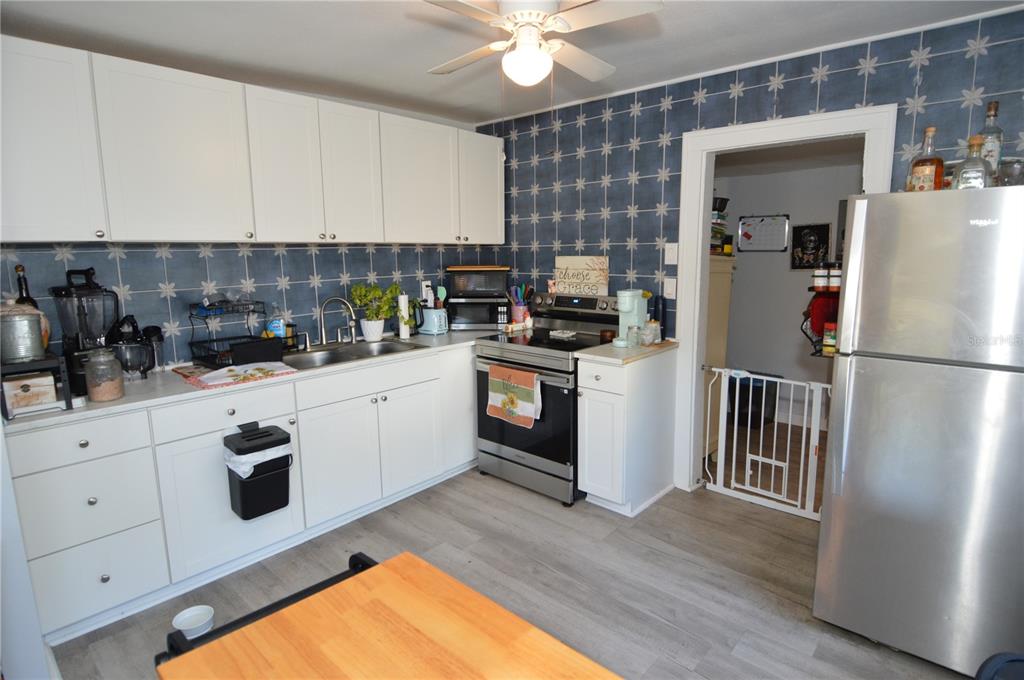 A kitchen features white cabinets, stainless steel appliances, and blue patterned wallpaper — 2852 60TH AVENUE N, ST PETERSBURG, FL