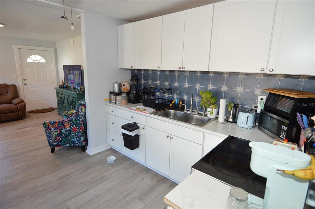 A kitchen features white cabinets, a blue patterned tile backsplash, and a stainless steel sink — 2852 60TH AVENUE N, ST PETERSBURG, FL