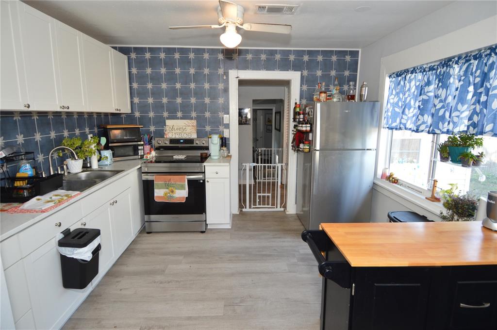 A kitchen features white cabinets, a stainless steel stove, a refrigerator, and blue patterned wallpaper — 2852 60TH AVENUE N, ST PETERSBURG, FL