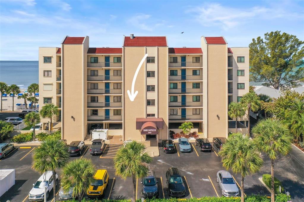 An exterior view of the Sand Castle III condominium building with a parking lot — 20040 GULF BOULEVARD UNIT 302, INDIAN SHORES, FL