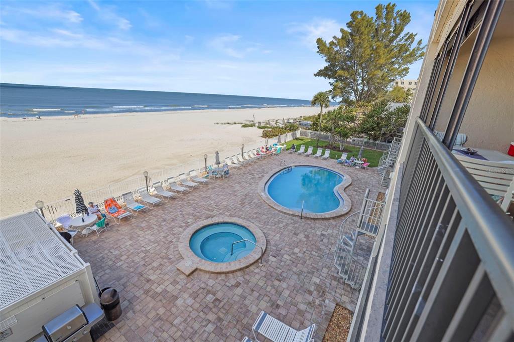 An elevated view of a beachside pool deck with a hot tub and lounge chairs — 20040 GULF BOULEVARD UNIT 302, INDIAN SHORES, FL