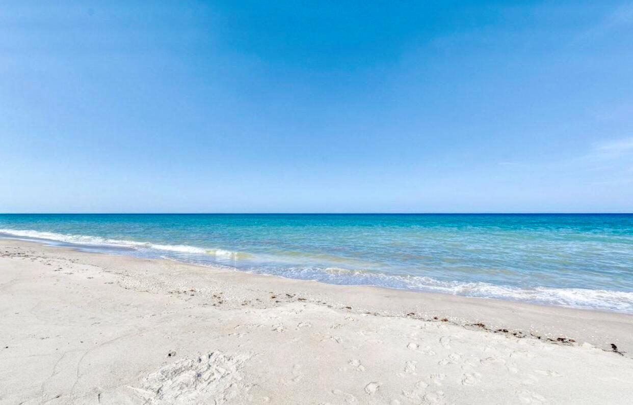 A wide, sandy beach meets the turquoise ocean under a clear blue sky — 420 Celestial Way # 303, Juno Beach FL 33408, JUNO BEACH, FL