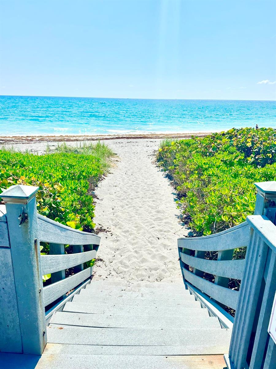 A wooden staircase leads down to a sandy beach path surrounded by lush green vegetation — 420 Celestial Way # 303, Juno Beach FL 33408, JUNO BEACH, FL