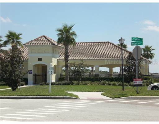 A community clubhouse with a tile roof, palm trees, and street signs at an intersection — 3000 LAUREL PARK LANE UNIT 207, KISSIMMEE, FL