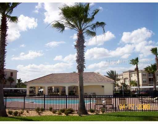 A swimming pool with a covered pavilion and palm trees in front of apartment buildings — 3000 LAUREL PARK LANE UNIT 207, KISSIMMEE, FL