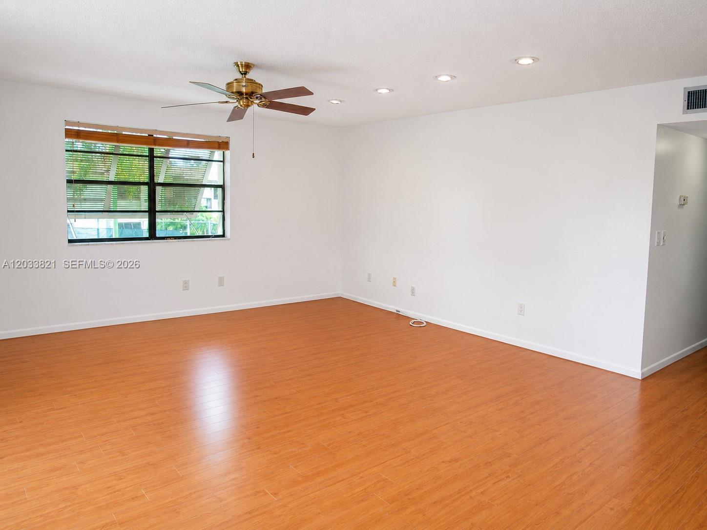 An empty room features white walls, wood-look flooring, a ceiling fan, and recessed lighting — 7935 SW 86th St # 823, Miami FL 33143, MIAMI, FL