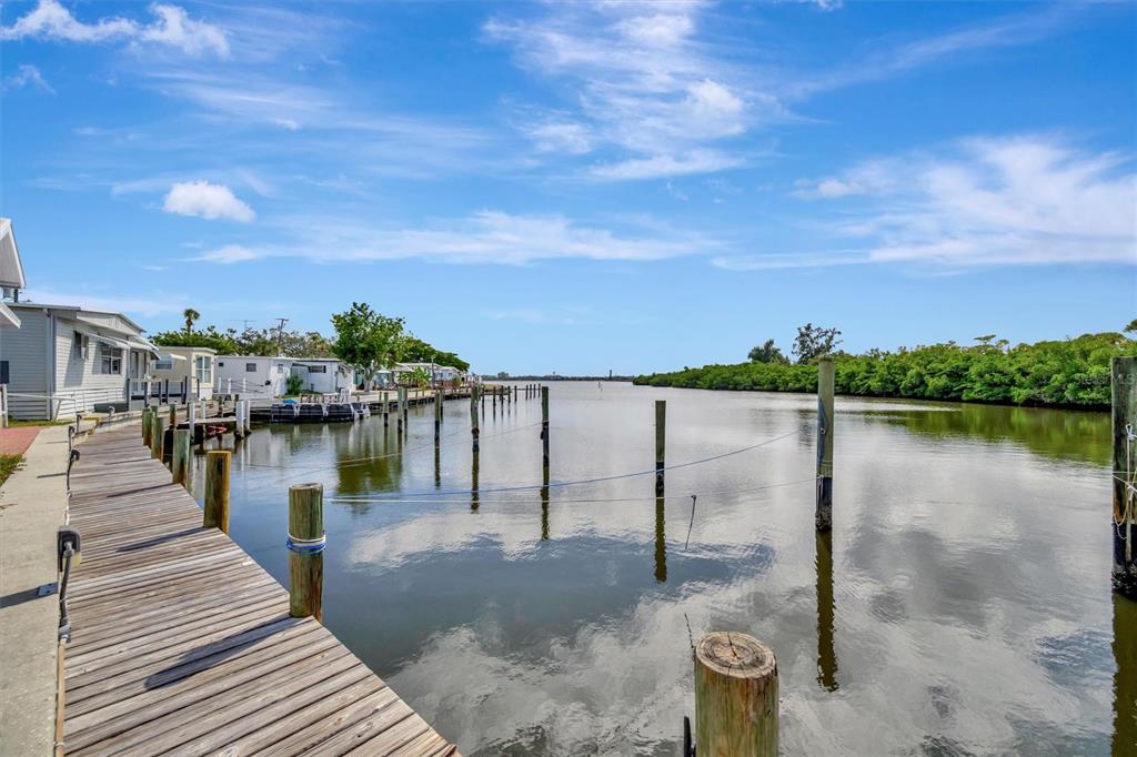 A wooden dock extends along a canal lined with mobile homes and lush green trees — 247 PALM LANE, PALMETTO, FL