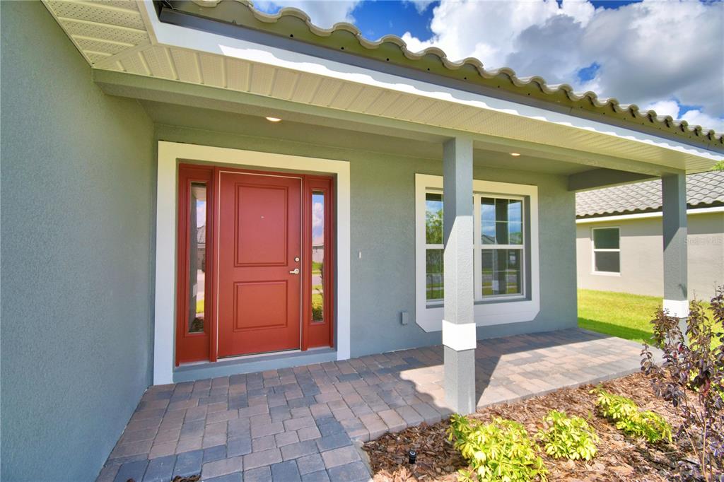 A hallway with light-colored tile flooring leads toward an open-concept kitchen and living area — 4944 VUE DE LAC PASS, AUBURNDALE, FL