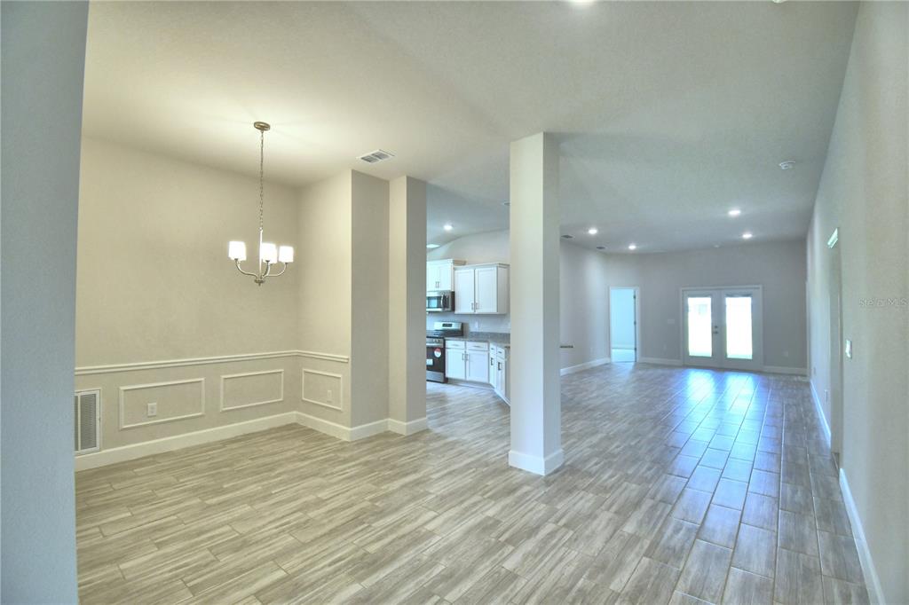 A bright dining area with wainscoting and tile flooring opens to an entryway and kitchen — 4944 VUE DE LAC PASS, AUBURNDALE, FL
