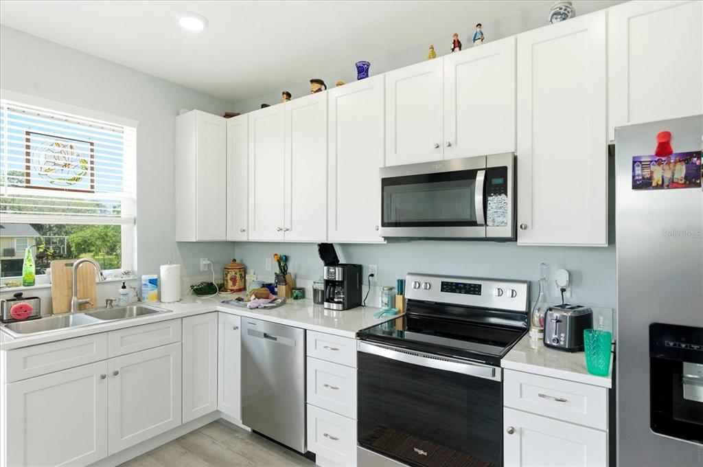 A kitchen features white cabinets, stainless steel appliances, and light-colored countertops — 3605 EAGLE NEST DRIVE, HERNANDO BEACH, FL