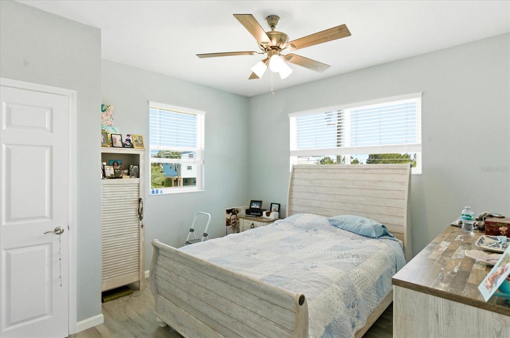 A bedroom features a light-colored bed, a ceiling fan, and two windows with blinds — 3605 EAGLE NEST DRIVE, HERNANDO BEACH, FL