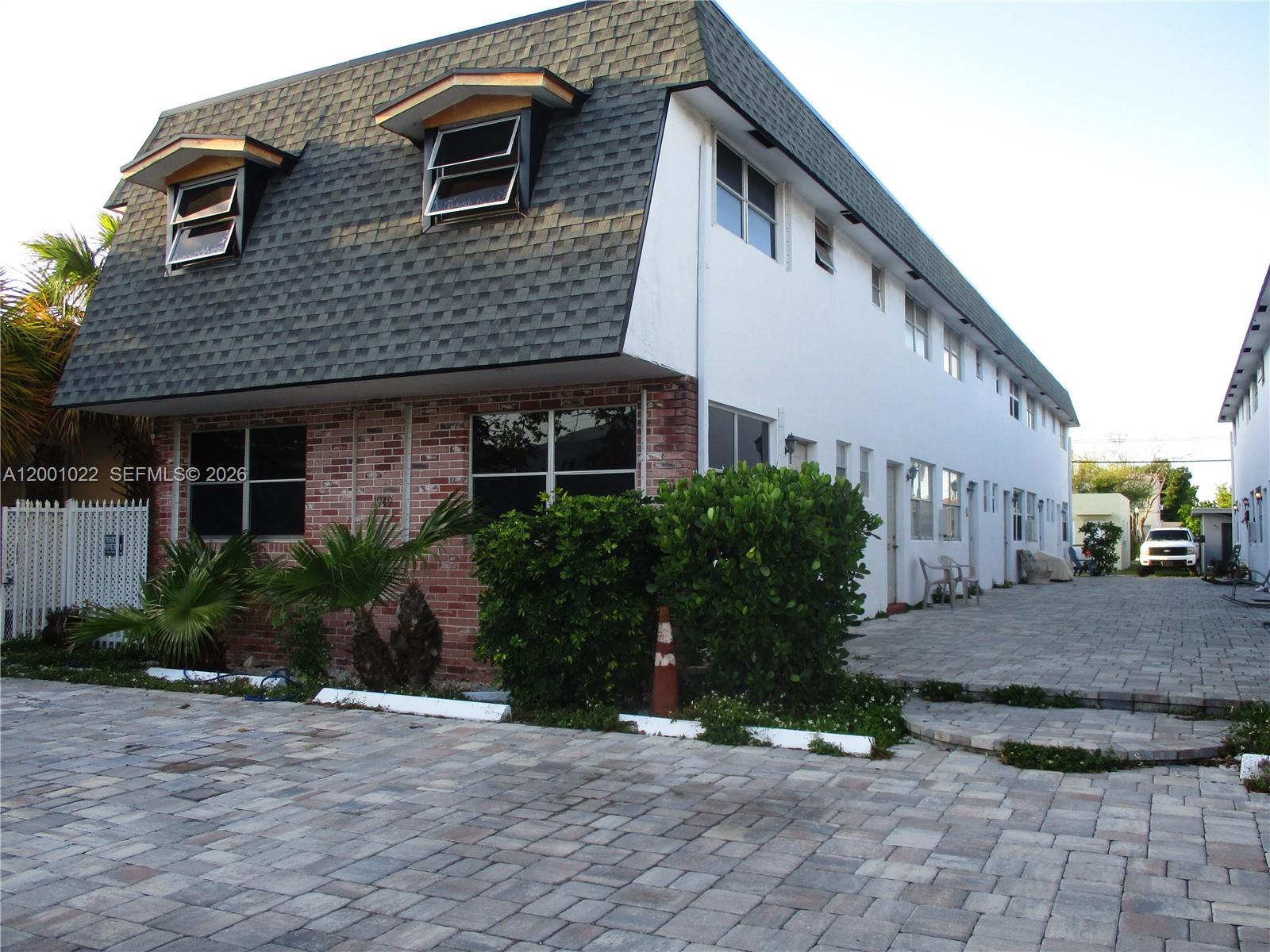 A two-story apartment building features a mansard roof, brick facade, and a paved parking area — 1949 Taylor St # 9, Hollywood FL 33020, HOLLYWOOD, FL