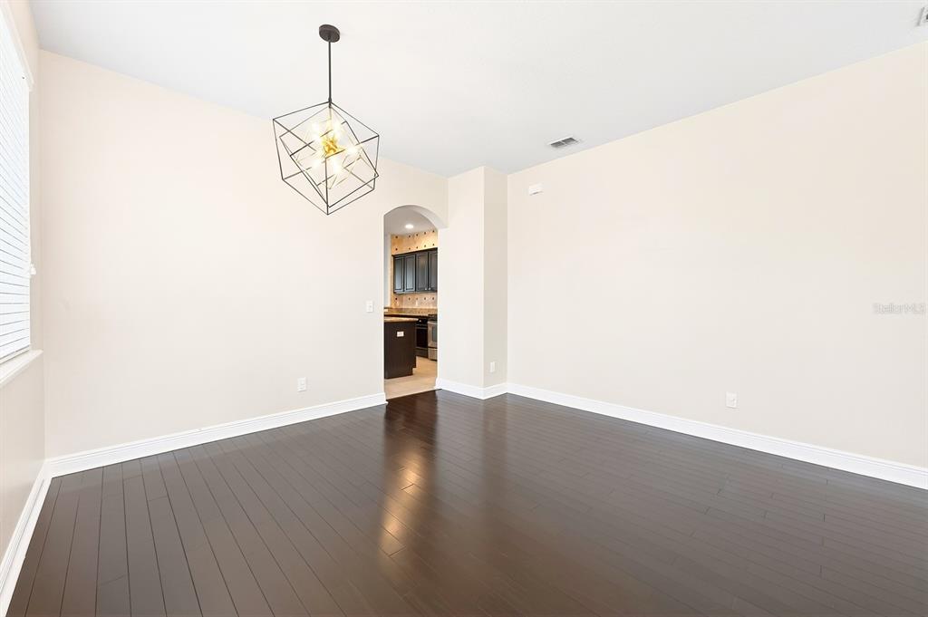 An empty room with dark hardwood floors, light-colored walls, and two windows — 918 SEBURN ROAD, APOPKA, FL
