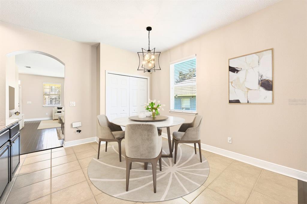 An empty dining room features dark hardwood floors, beige walls, and a geometric pendant light — 918 SEBURN ROAD, APOPKA, FL