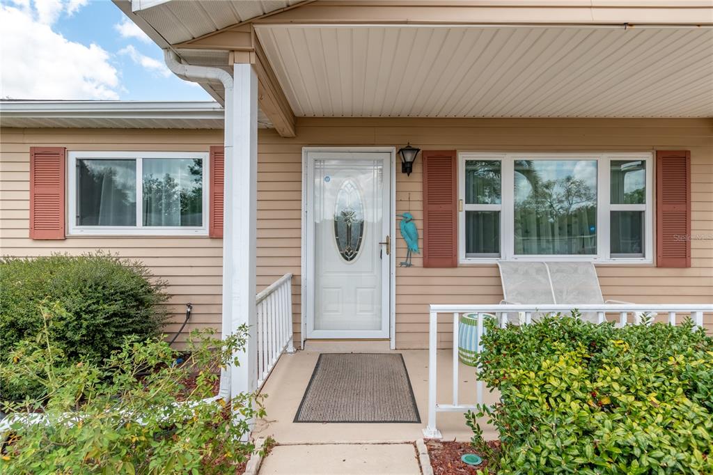 The exterior of a house features beige siding, red shutters, and a covered front porch — 8417 SW 106TH STREET, OCALA, FL