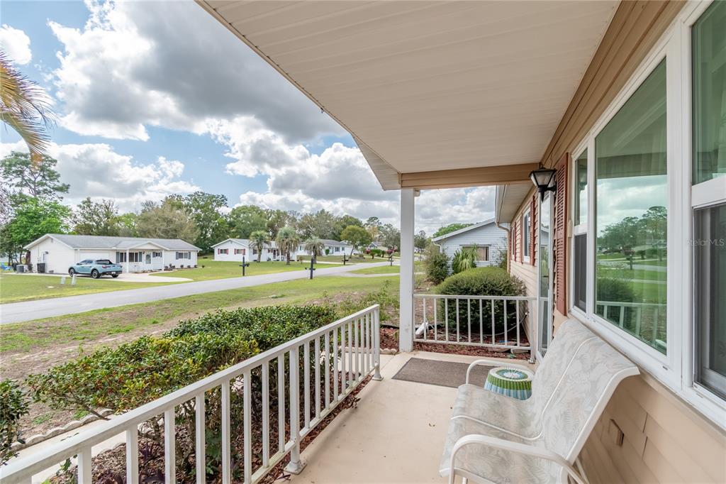 A covered porch with a white railing overlooks a residential street with neighboring houses — 8417 SW 106TH STREET, OCALA, FL