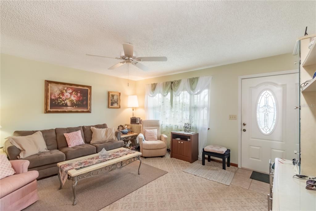 A living room features a brown sofa, a beige armchair, and a white front door — 8417 SW 106TH STREET, OCALA, FL