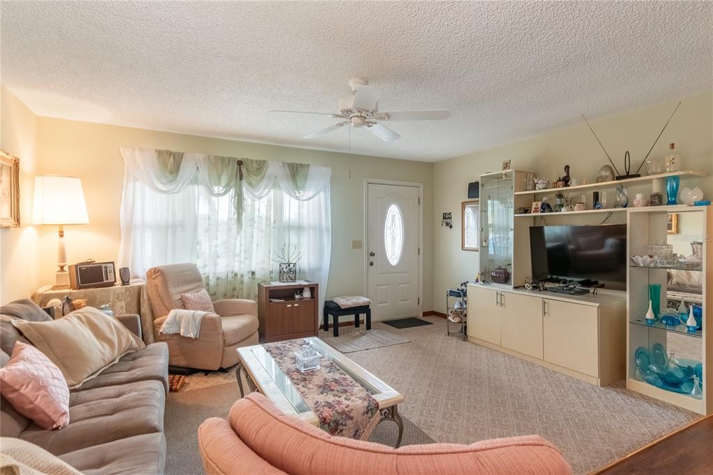 A living room features a sofa, armchair, coffee table, television console, and a front door — 8417 SW 106TH STREET, OCALA, FL