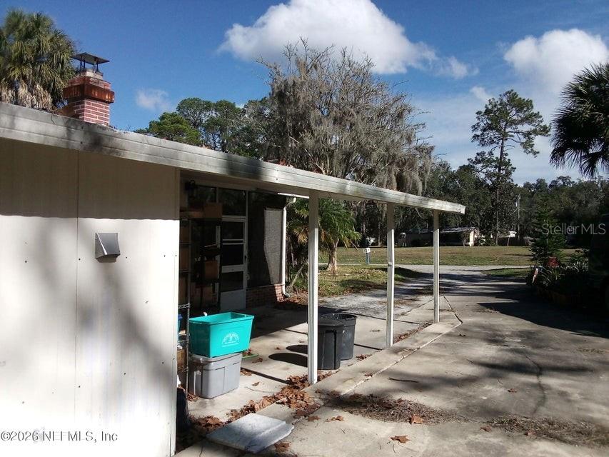 A covered concrete patio area features a brick chimney and a view of the yard — 101 S GERALDO ROAD, EAST PALATKA, FL