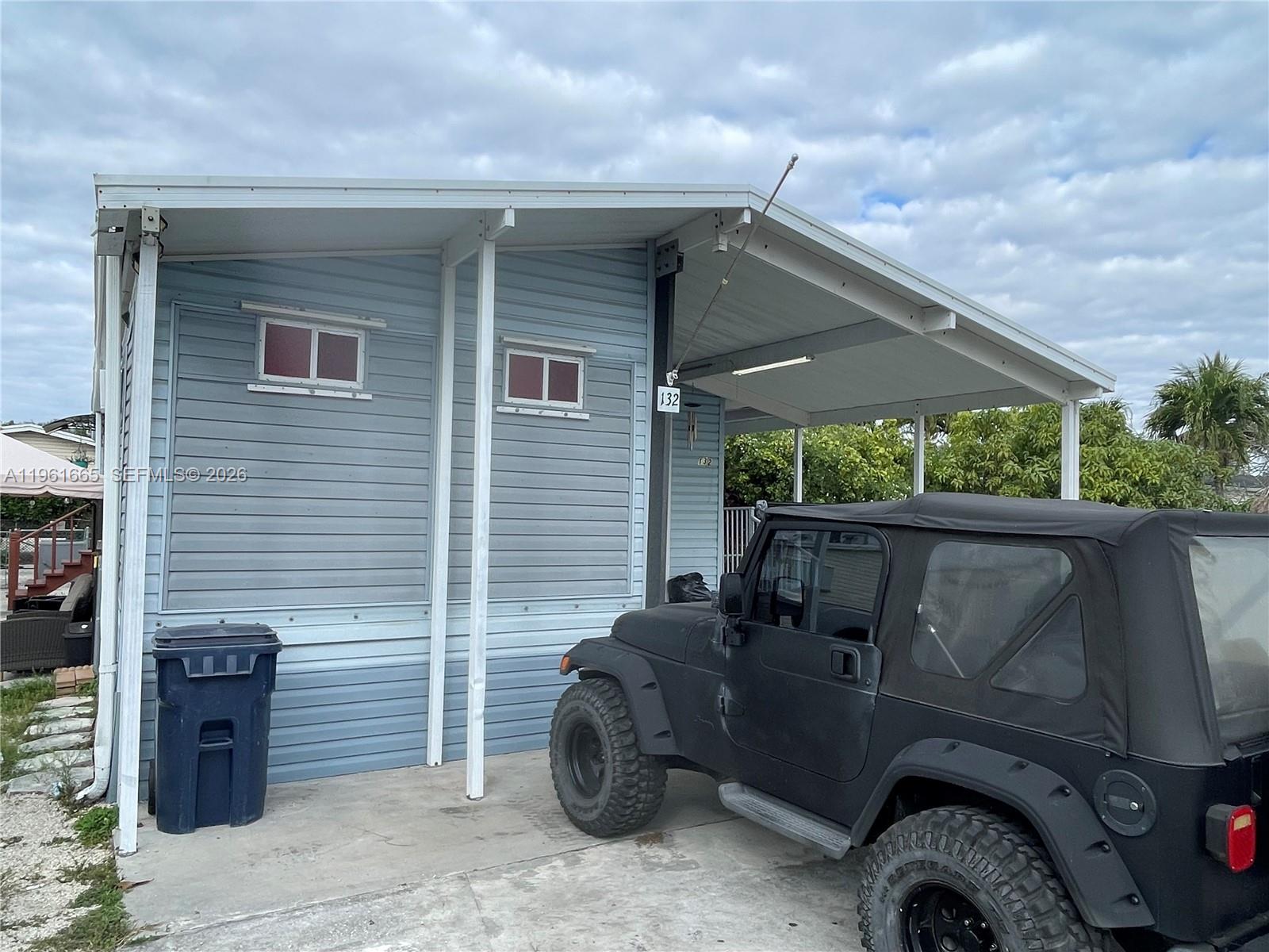 A light blue mobile home exterior features a carport, two small windows, and a black Jeep — 19800 SW 180th Ave UNIT 132, Miami FL 33187, MIAMI, FL