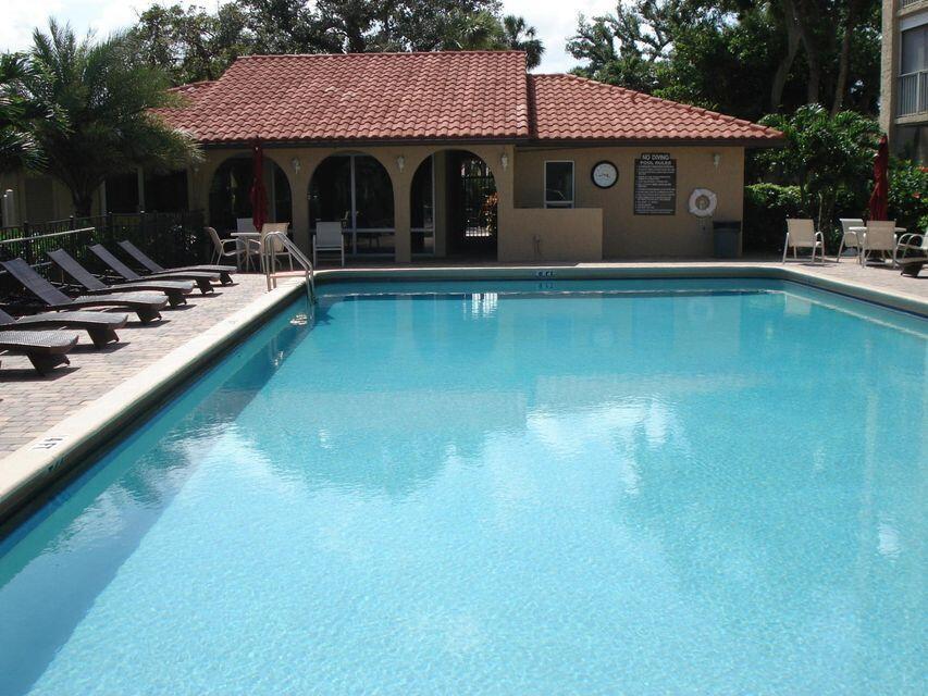 A rectangular swimming pool sits in front of a building with a red tile roof — 950 Ponce De Leon Road # 5010, Boca Raton FL 33432, BOCA RATON, FL