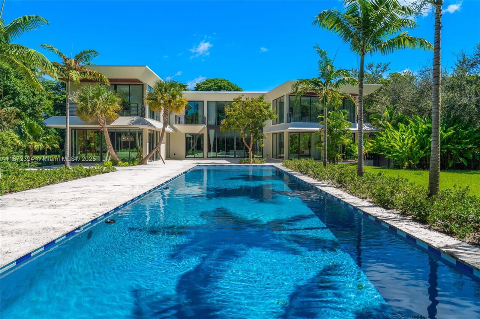 A modern two-story house with a long swimming pool and palm trees in the backyard — 9440 Old Cutler Ln, Coral Gables FL 33156, CORAL GABLES, FL